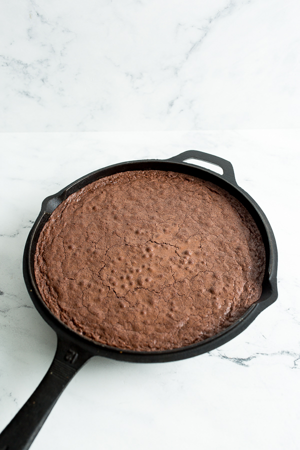 Angled photo of the number 12 cast iron skillet with the finished baked brownies, uncut, on white marble countertop.