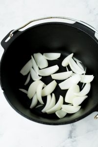 adding the cut onions to the pot to cook
