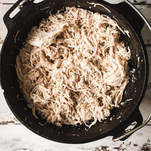 Overhead image of a cast iron dutch oven with shredded chicken.
