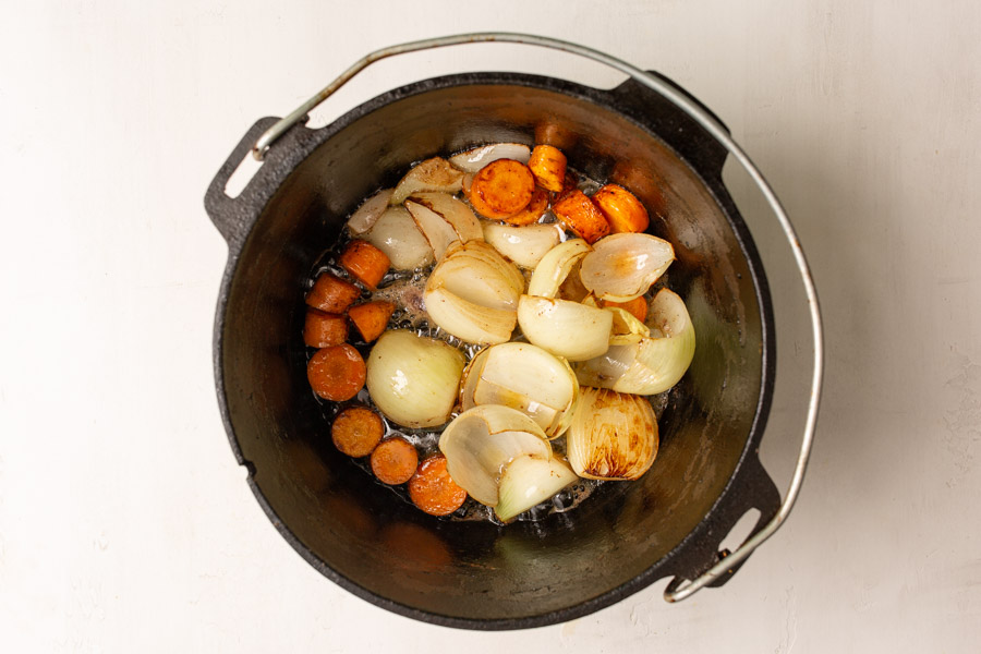 Overhead image of carrots and onions in a dutch oven.