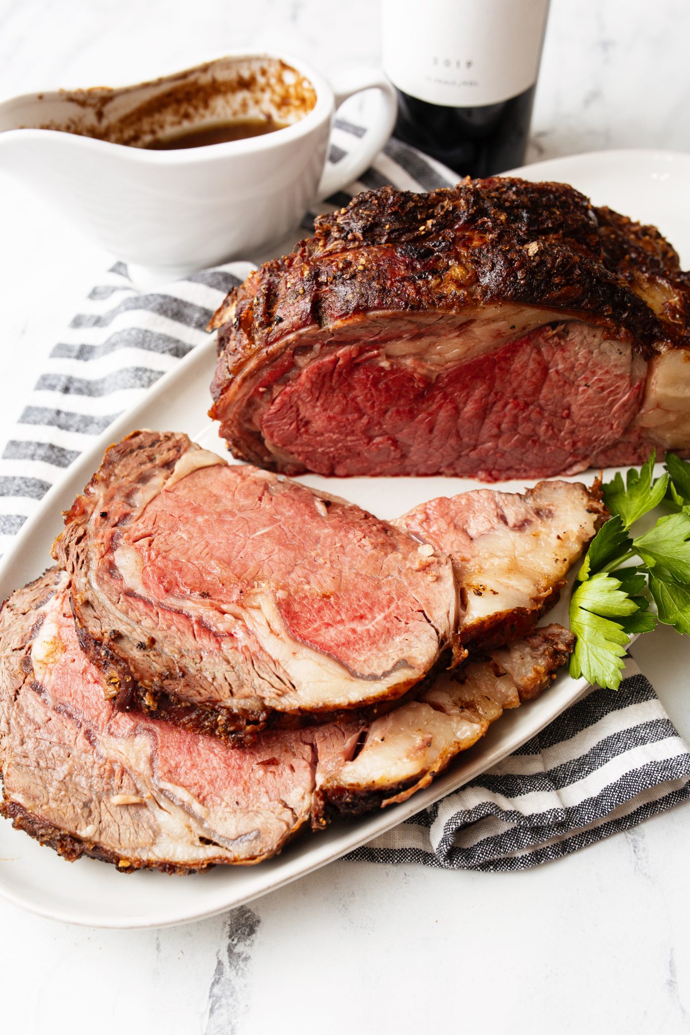 Side shot of the easiest prime rib recipe sliced and roast with au jus and red wine