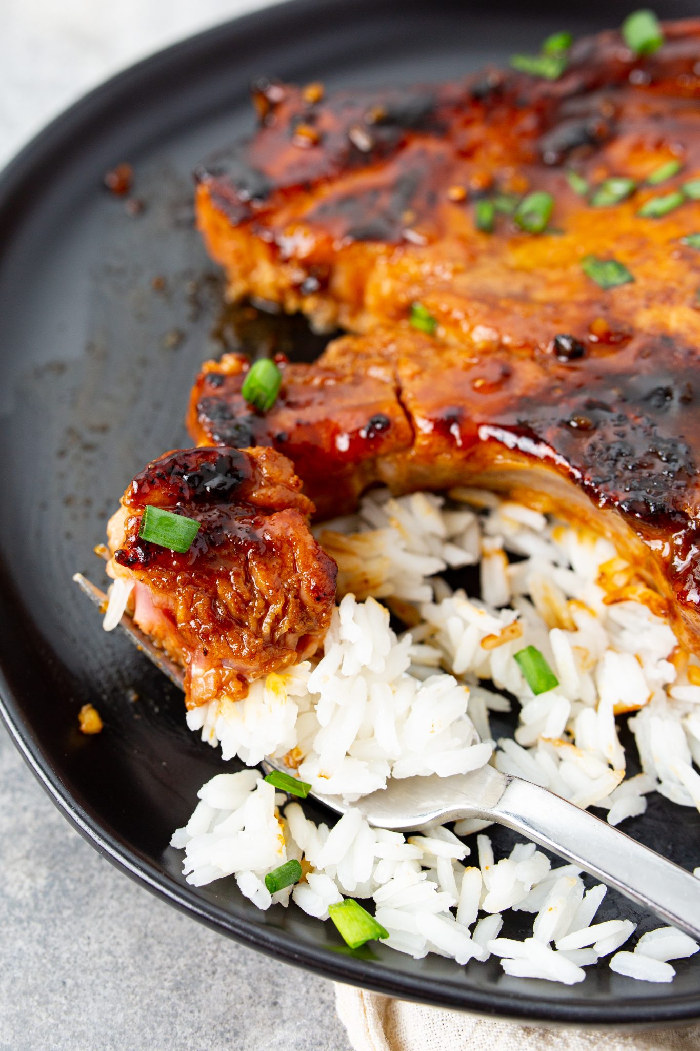 Asian Style Hoisin Glazed Bone In Pork Chops served with rice and garnished with chives