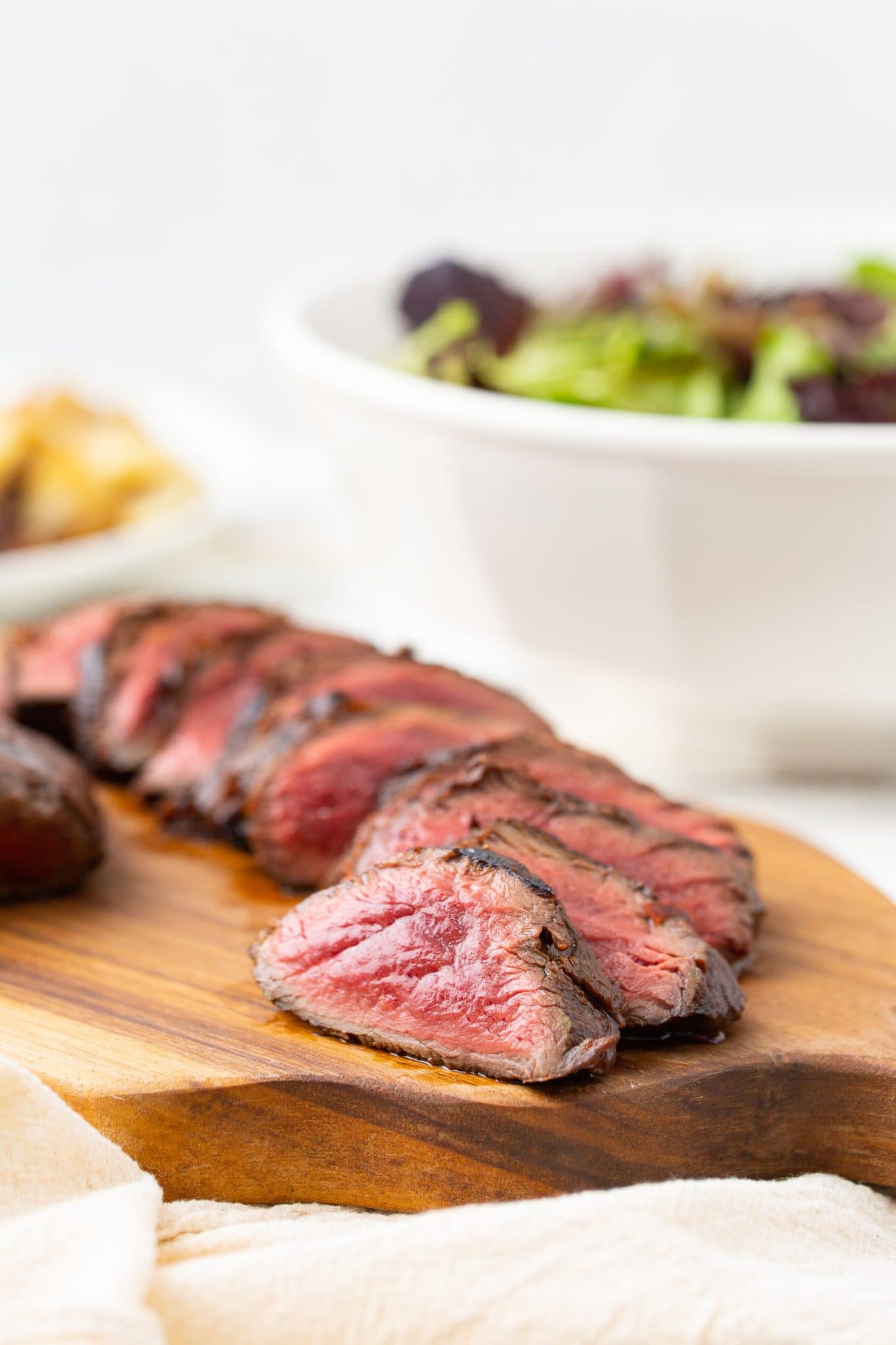 Close up image of grilled venison backstrap tenderloin cut into medallions and served on a cutting board