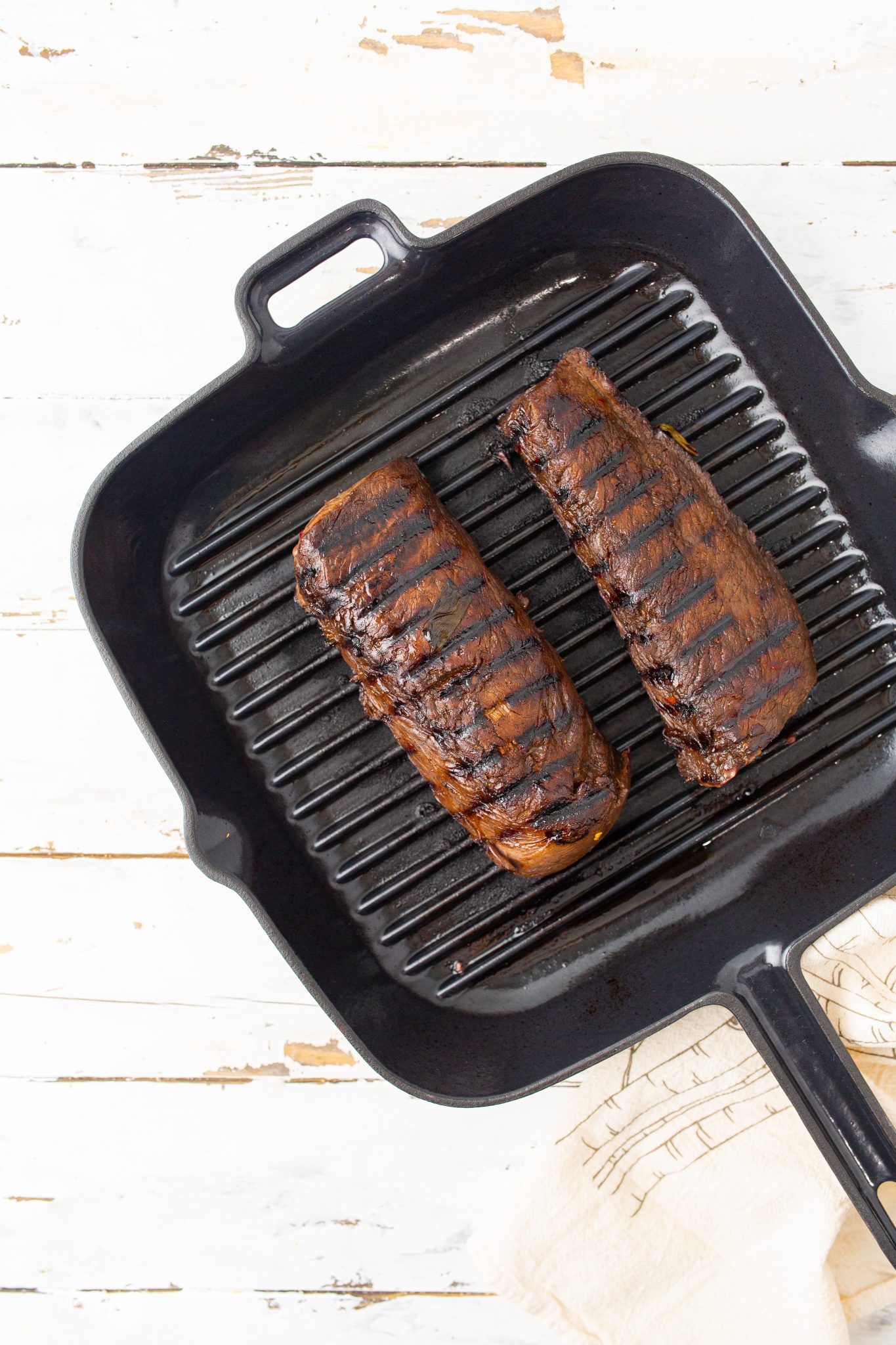 overhead image of grilled venison backstrap on a cast iron grill pan