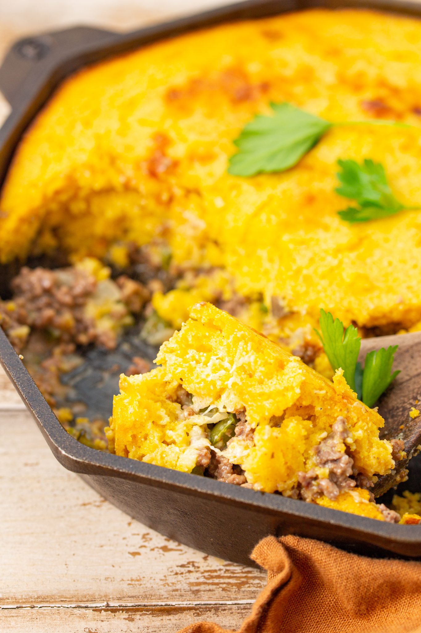 featured cornbread casserole with ground beef in a cast iron skillet. 