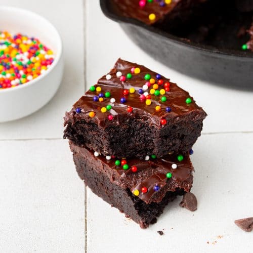 Cosmic brownies stacked in front of a cast iron skillet