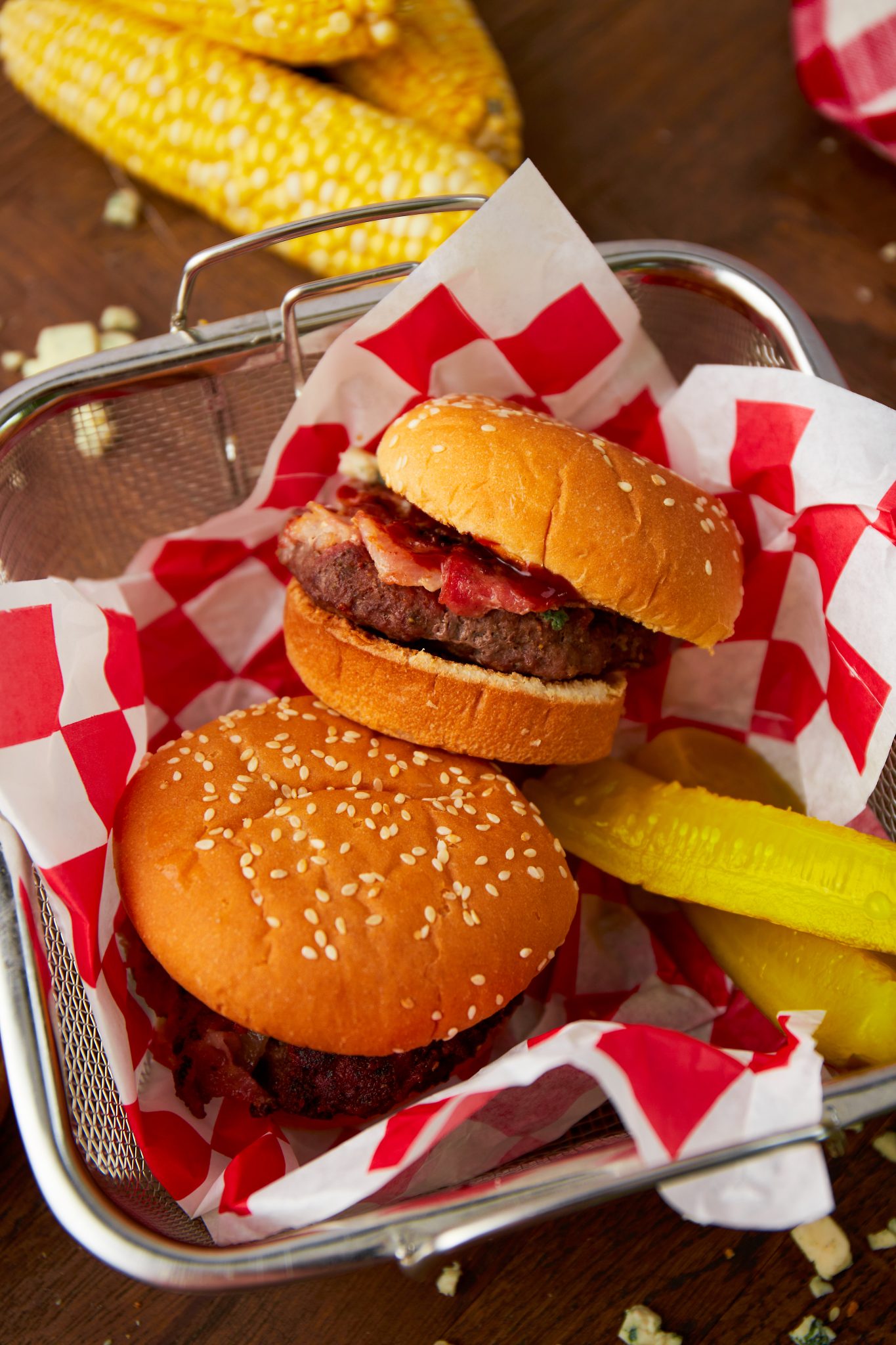 Two bacon cheeseburgers in a serving platter with pickles