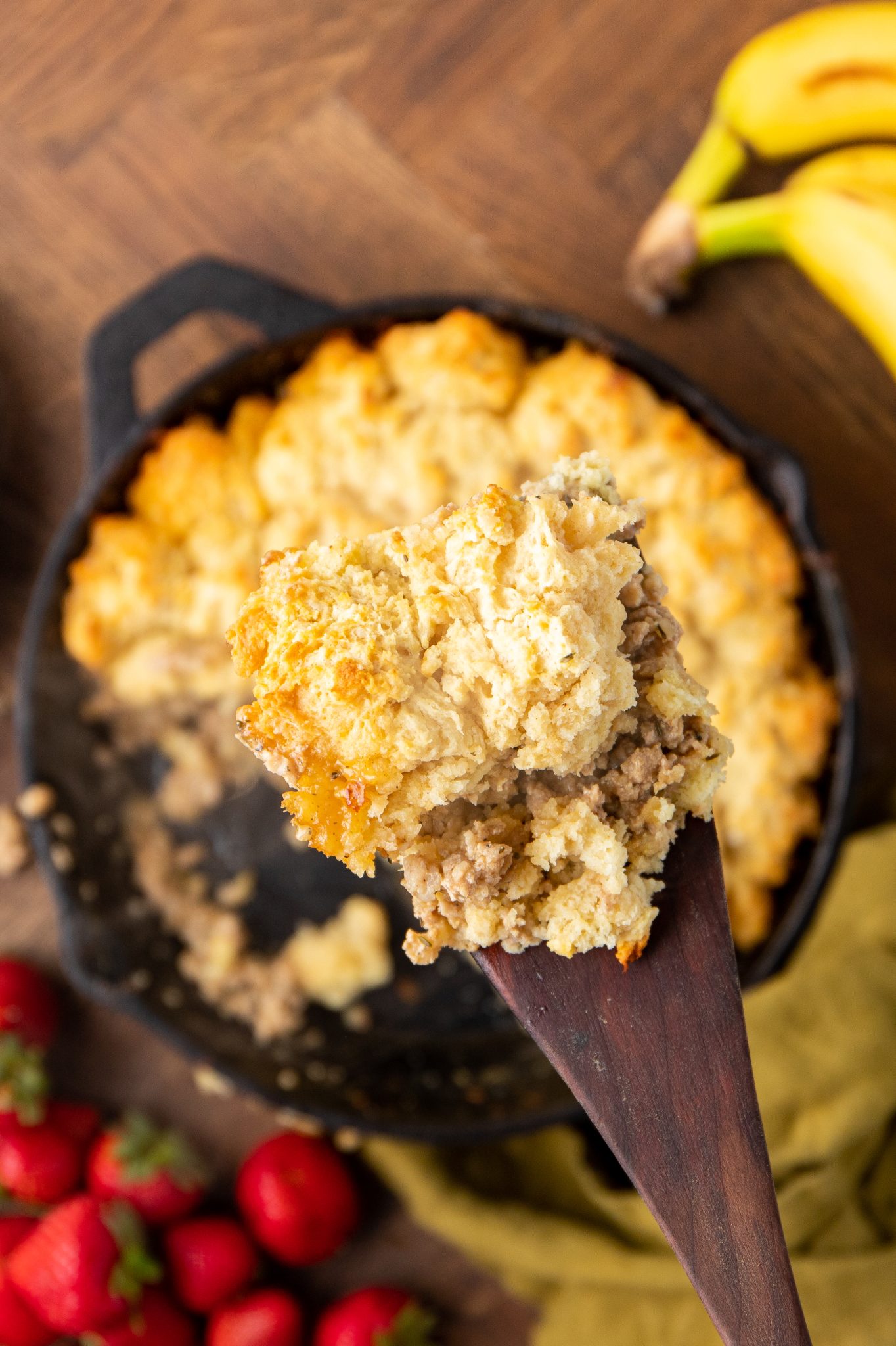 spoonful of sausage biscuit casserole hovering over a cast iron skillet