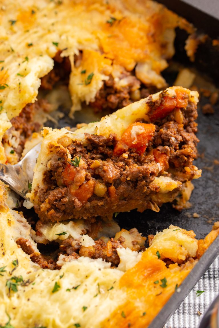 A close up image of cottage pie being served from a cast iron casserole dish