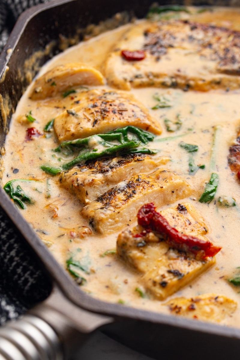 creamy chicken with sun-dried tomato and spinach sauce in a cast iron skillet