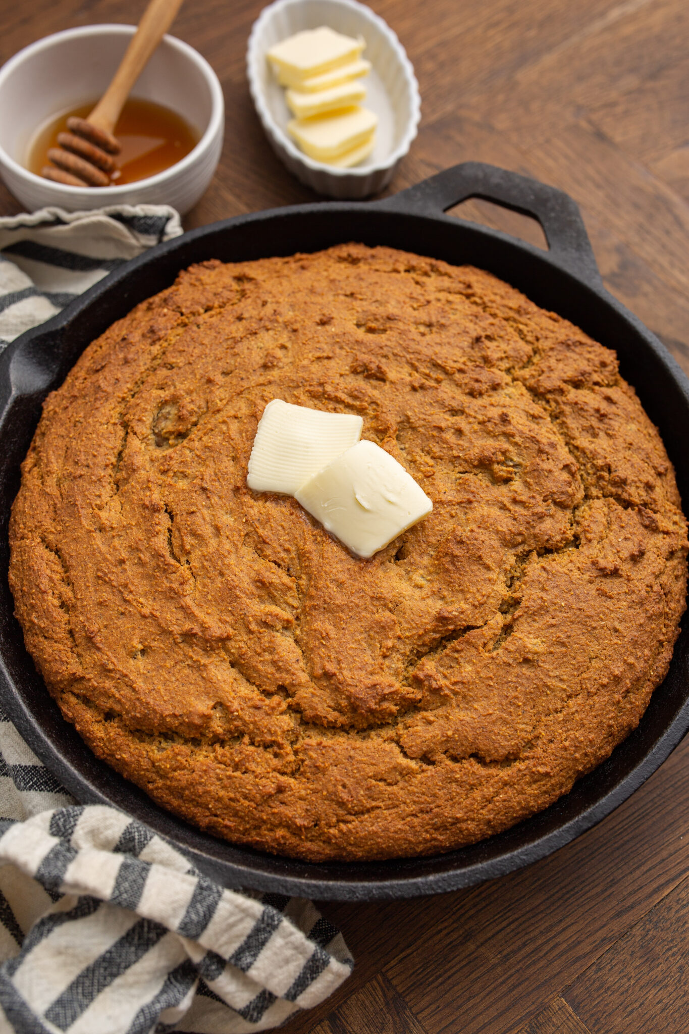 skillet of sweet potato cornbread with pads of butter on top